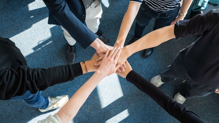 Gruppe von Menschen die Hände in der Mitte übereinander halten